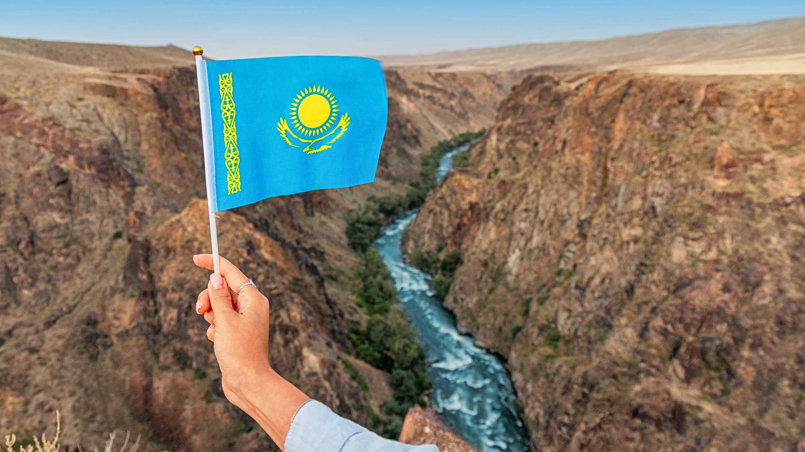 kazakhstan-flag-infront-of-charyn-canyon-kazakhstan-shutterstock2664132171